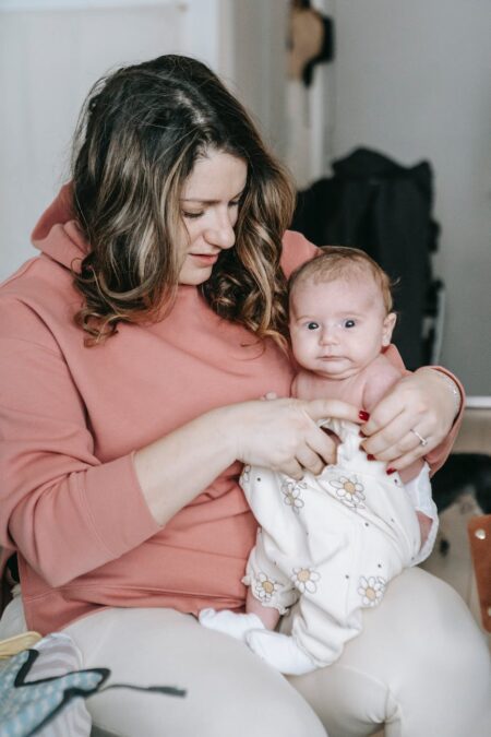 mother putting clothes on her baby